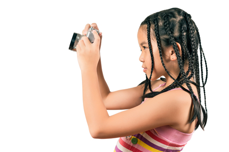 Portrait of the little girl with vintage camera isolated on a white background, photographing somethingの写真素材