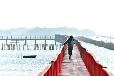Walking over the wooden red bridge across the sea at Gulf of Thailand, near by Tha Chin estuary, Samutsakhon province, Thailandの写真素材