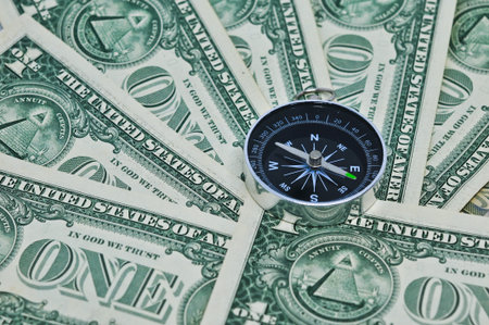 Compass laying on a pile of on dollar bills, finance and money concept