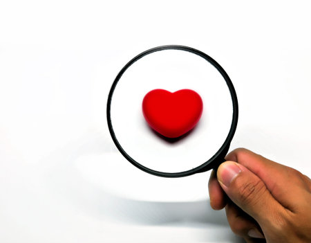 Red heart through a magnifying glass, isoleted on white background. Searching for love or find love....