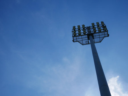 Sports light pole or Stadium Light tower in sport arena on blue sky with clouds and copy space..