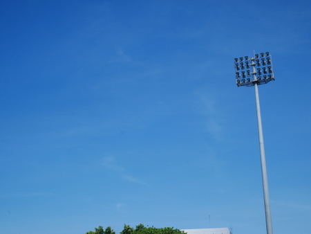 Sports light pole or Stadium Light tower in sport arena on blue sky with clouds and copy space.の写真素材