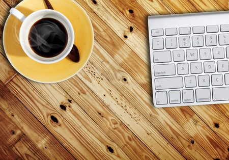 computer keyboard and a cub of coffee on wood tableの写真素材
