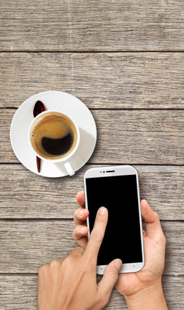 Hand holding White Smart phone on wood coffee tableのeditorial素材