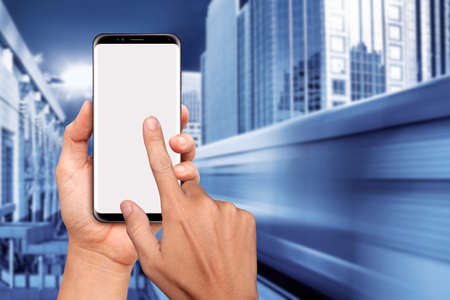 Hand Holding Smart phone with downtown Sky Train blurry backgroundの写真素材