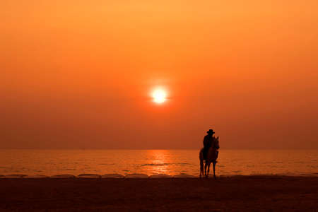 Horse riding on the beach at sunsetの写真素材