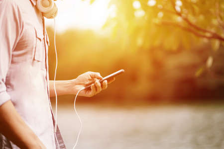 a Man listening to a music from a smartphone with garden backgroundの写真素材