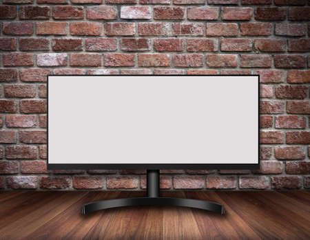 Modern Computer Monitor on a wooden desk with Old Brick wallの写真素材