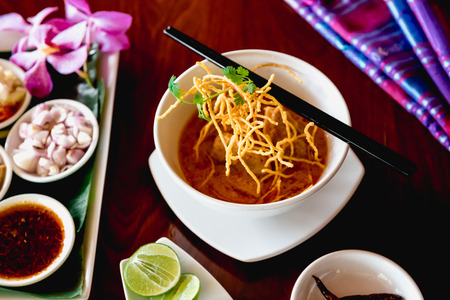 A beautiful set of Khao Soi, local northern food of Thailand. Khao soi is checken with curry with crispy noodle on top. Eat with traditional side dishes.の写真素材