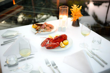 Luxury romantic candle light dinner setup by the pool with plate of lobster and seafood BBQの写真素材