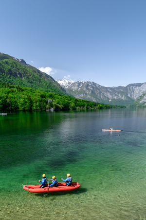 Concept picture of summer time at lake bohinj in Slovenia with red canoe in emerald color lake.の写真素材