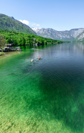 Concept picture of summer time at lake bohinj in Slovenia with red canoe in emerald color lake.の写真素材
