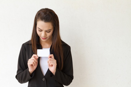 portrait of female business executive with hand holding and looking at blank card and extra textspace on her sideの写真素材