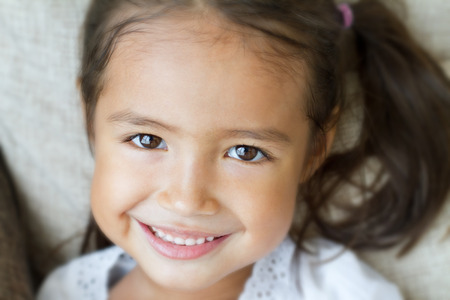 close-up portrait of happy, positive, smiling, playful asian caucasian girlの写真素材