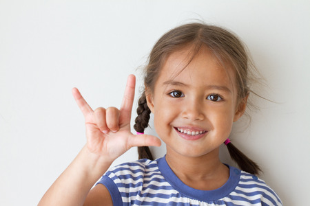 cute little girl showing I love you hand signの写真素材