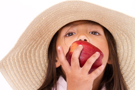 Cute little girl, hand holding, biting red appleの写真素材