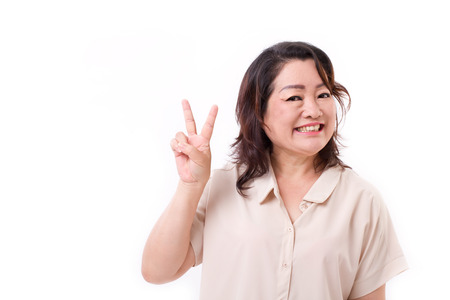 happy, confident middle aged woman pointing up v sign, victory, number 2 hand sign gestureの写真素材