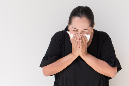  sick woman with cold or flu sneezing with tissue paperの写真素材