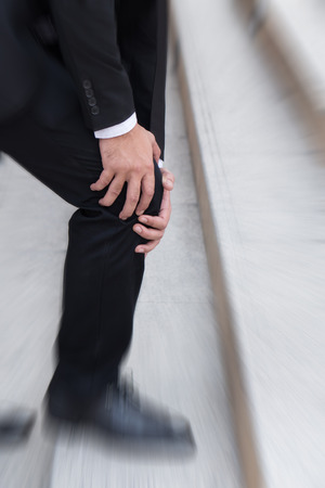 business man with knee pain, obstacle conceptの写真素材