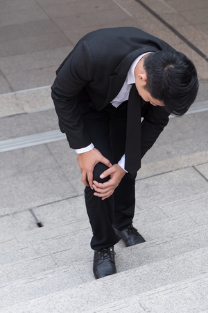 business man with knee pain, obstacle conceptの写真素材