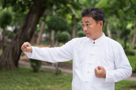 old man practicing kungfu or tai chi in the park, healthy lifestyle meditation exercise conceptの写真素材