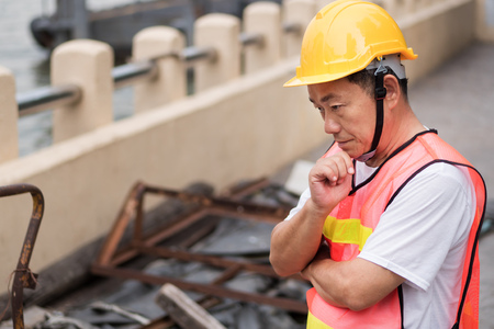 construction worker thinking, planning with pile of raw materialの写真素材