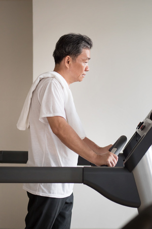 old senior man walking, running, exercising, working out in gym with threadmill machineの写真素材