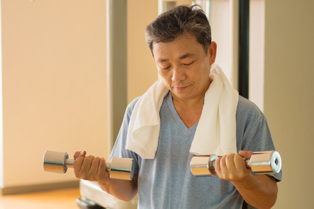 senior asian man working out, weight training with dumbbellの写真素材
