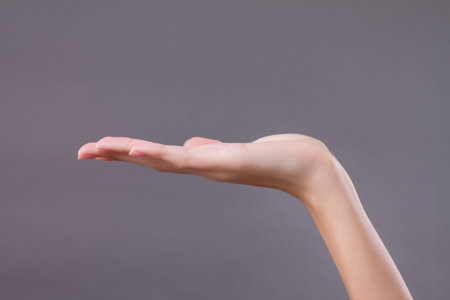 hand holding, receiving, carrying something on gray background