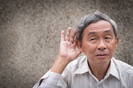 sad senior listening, old man hearing concept of deafness or hard of hearingの写真素材