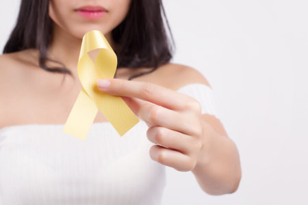 Woman hand holding yellow ribbon bow,  military forces, fire service, endometriosis awareness...