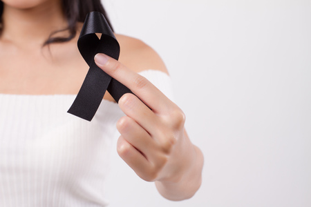 Woman hand holding black ribbon bow, sad unhappy mourning woman, studio white isolated of asian young adult modelの写真素材