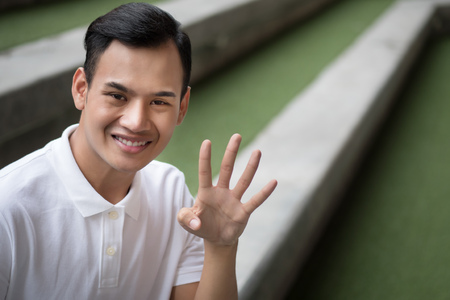 happy man pointing up four finger gesture; smiling friendly man pointing 4 number, number four fingers hand sign; guy points up number four hand sign concept of counting, numberingの写真素材