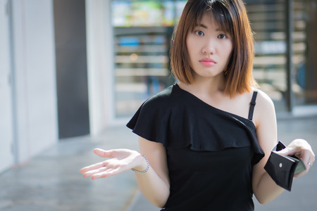 poor woman without money, empty wallet; portrait of poor woman with empty wallet, poor people, poverty, bankruptcy, financial broke, unemployment, no credit concept; asian young adult woman modelの写真素材