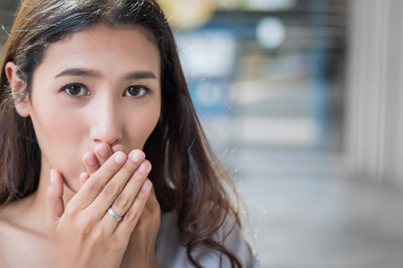 excited woman looking at you with surprise and interest; portrait of surprised, excited asian woman with exciting, oh, uh, ah, wow interesting face expression; asian young adult woman model, urban city environmentの写真素材