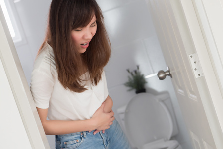 woman with diarrhea symptom; sick woman suffering from diarrhea, stomachache, menstrual period cramp, abdominal pain, food poisoning, gastritis, constipation; asian young adult woman health care modelの写真素材