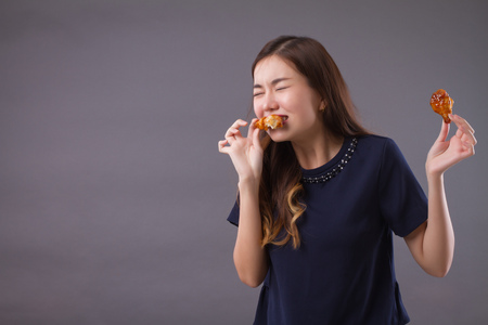 woman eating unhealthy fat fried chicken; portrait of unhealthy girl eating fat fried chicken, fast food; unhealthy eating, dining with high cholesterol fat concept; asian chinese 20s woman modelの写真素材