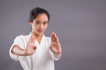 woman fighter portrait; asian woman practicing martial arts, mixed martial arts, MMA, kick boxing, karate studio isolated portrait; girl fighter training concept; 20s young adult asian woman modelの写真素材