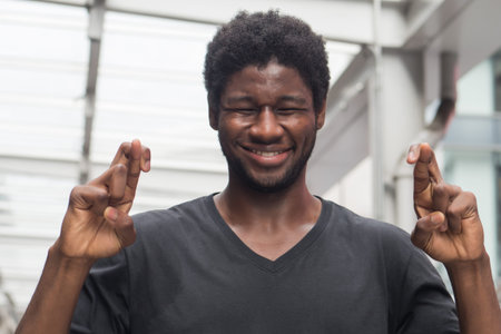 african man crossing his finger; portrait of african man or black man with crossed finger, wishing...