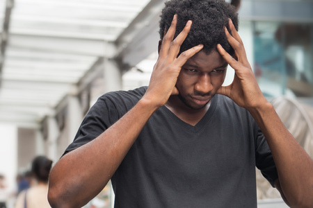 portrait of stressed sick african man with headache; ill african man or black man suffers from headache, vertigo, dizziness, migraine, stress, depression, hangover concept; adult african man modelの写真素材