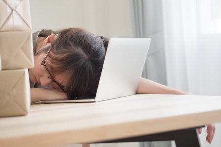 exhausted asian woman business working overnight and sleep at work desk; portrait of tired,...