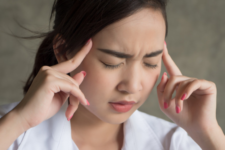 portrait of stressed sick woman with headache; ill woman suffers from vertigo, dizziness, migraine, hangover, health care concept; young adult asian woman modelの写真素材