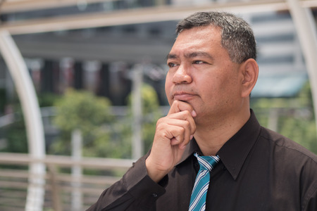 thoughtful old man thinking, stressful senior man planning; portrait of stressed, serious, hopeless, desperate asian man thinking, planning with headacheの写真素材