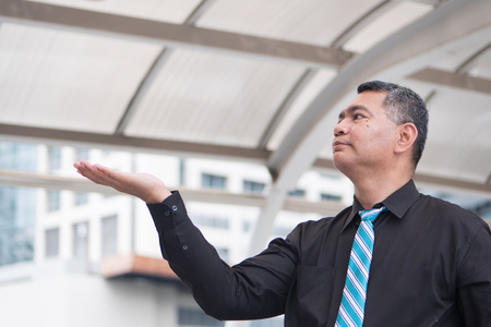 old business man pointing up, showing, presenting concept; portrait of confident, successful asian business man pointing finger or pointing hand up to blank space; 50s old south east asian man modelの写真素材