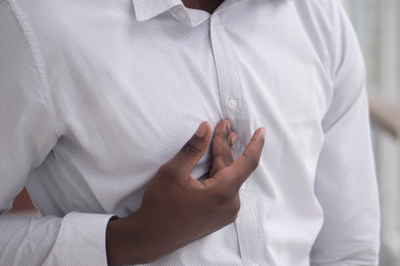 African man suffering from acid reflux or GERD; sick stressed black man with indigestion, acid...
