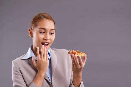 Happy smiling Asian woman eating pizza; Portrait of south east Asian woman holding delicious italian pizza; enjoy eating pizza concept; Asian young adult, tan skin woman modelの写真素材