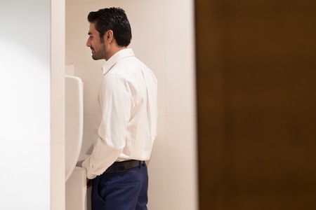 Asian man urinating in toilet; portrait of Indian man using water closet, WC for peeing; concept of health care, prostate cancer, urethritis, UTI or urinary tract infection; Asian adult man modelの写真素材