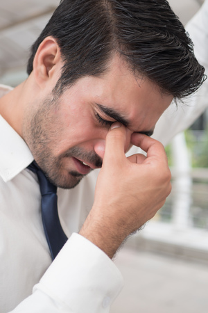 depressed asian business man; portrait of sick indian asian man with depression suffering from headache, vertigo, hangover, migraine, stressの写真素材