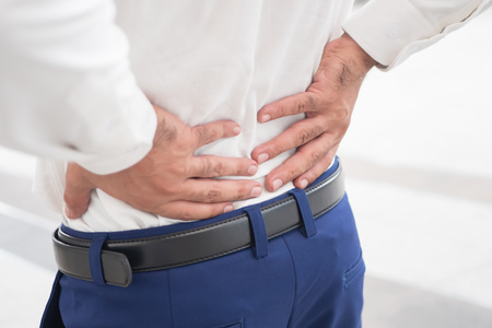 Sick unhealthy asian man suffering from back pain, spine problem, hernicated disc, spinal disc dislocation or displacement, office syndromeの写真素材