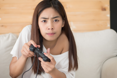 excited woman playing console video game. portrait of excited and fun asian woman plaing vdo game. hobby, liesure activity concept. asian young adult woman modelの写真素材